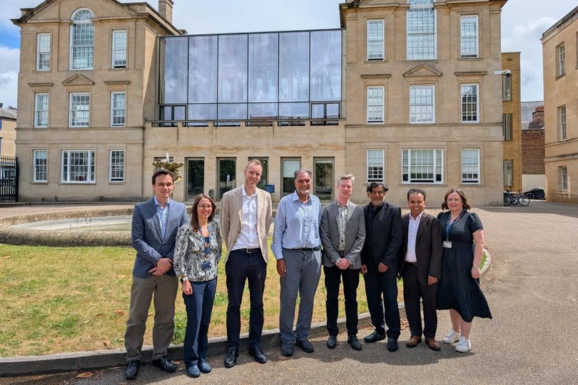 A group of eight people stand in front of a building. 