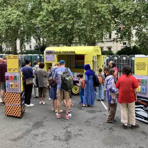 People standing around in front of a yellow horsebox that says Meat Your Persona